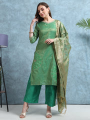 Woman wearing a green traditional outfit with a matching dupatta against a blue wall.